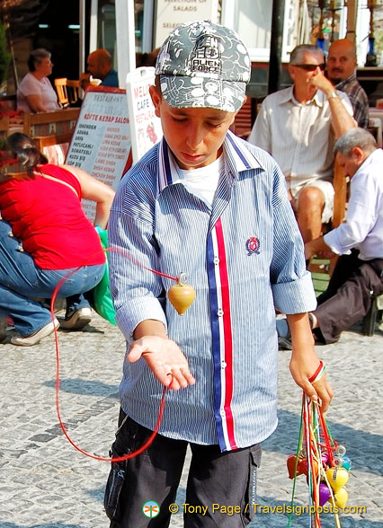 Young vendor selling spinning tops to tourists