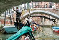 The skillful gondolier navigates under the many bridges
