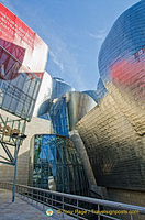 Guggenheim Bilbao's Titanium catches the red and blue of nearby structures
