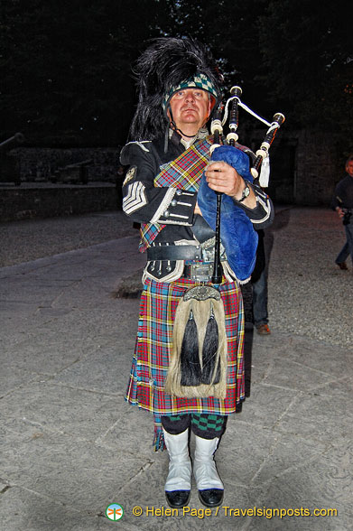A lone piper plays as guests arrive