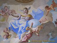 In the center of the ceiling is a female figure. She is the allegory of Faith