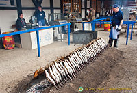 Neat rows of steckerlfisch being grilled