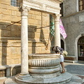 Me, peering down the ancient well in Piazza Pio II