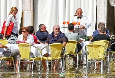 With feet in water, these tourists are enjoying drinks at the Cafe Lavena