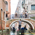 People on the bridge enjoying the flottila of gondolas cuising by