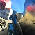 Guggenheim Bilbao's Titanium catches the red and blue of nearby structures
